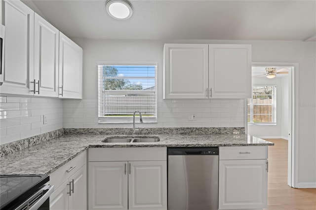 kitchen with white cabinets, dishwasher, a sink, and light stone counters
