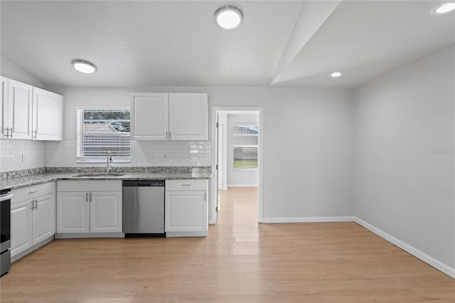 kitchen featuring tasteful backsplash, a sink, white cabinetry, appliances with stainless steel finishes, and light stone countertops