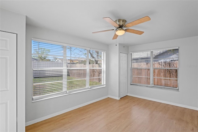 spare room with baseboards, a ceiling fan, wood finished floors, and plenty of natural light