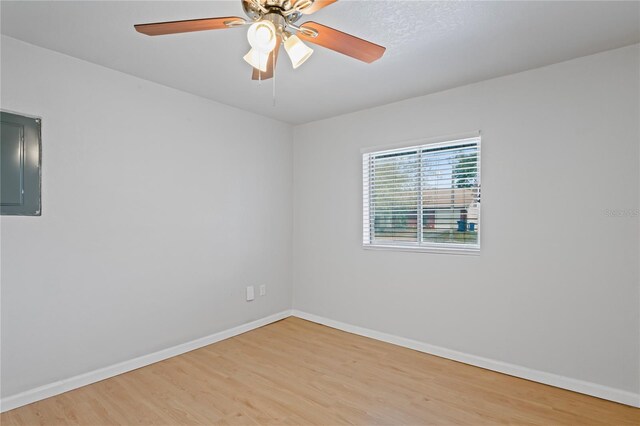 spare room featuring baseboards, electric panel, and light wood-style flooring