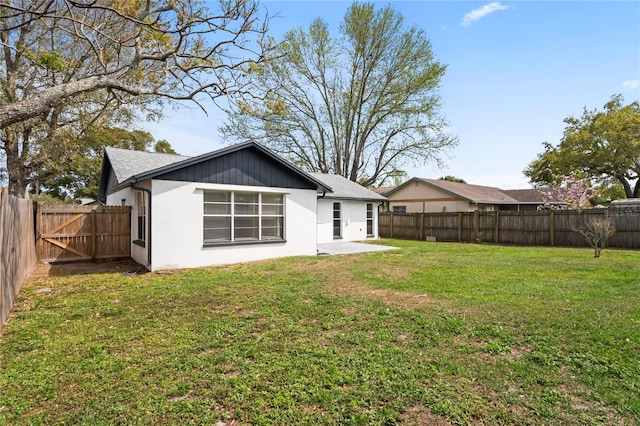 back of property with a fenced backyard, a gate, a yard, a patio, and stucco siding