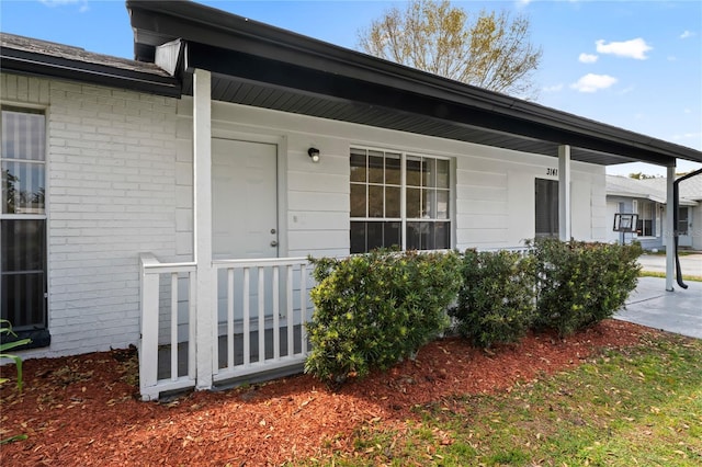 entrance to property featuring brick siding and a porch