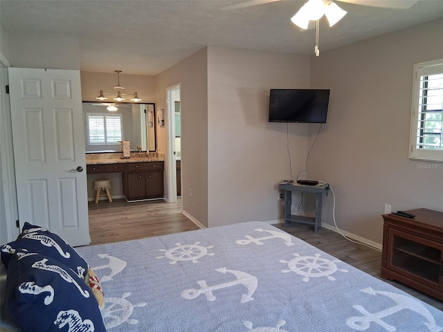 7508 Cypress Knee Dr, Hudson, FL 34667 - bedroom featuring wood finished floors, baseboards, ensuite bath, and a desk
