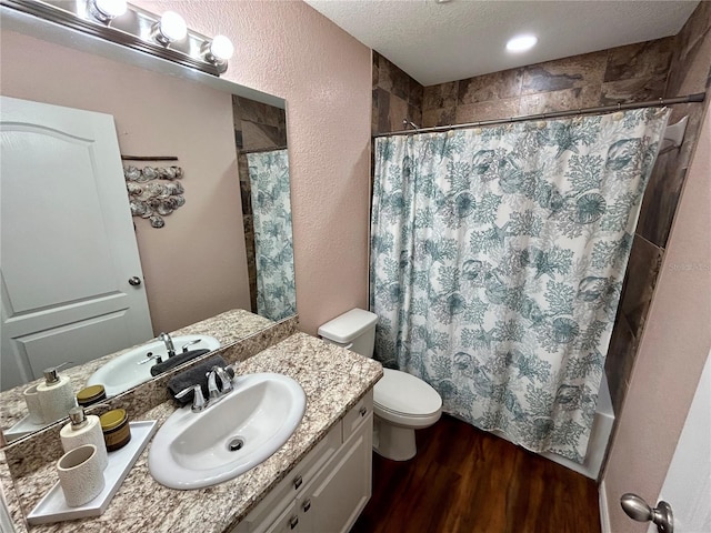 bathroom featuring wood finished floors, toilet, vanity, shower / tub combo with curtain, and a textured ceiling