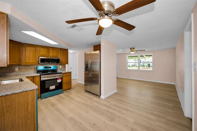 7321 Parrot Dr, Port Richey, FL 34668 - kitchen featuring light wood finished floors, stainless steel appliances, backsplash, a sink, and brown cabinetry