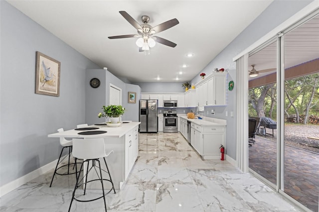 kitchen featuring light countertops, stainless steel appliances, a ceiling fan, and baseboards