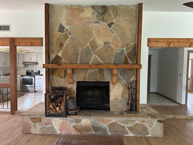 1412 Wexford Dr N, Palm Harbor, FL 34683 - interior details with visible vents, wood finished floors, a fireplace, under cabinet range hood, and stainless steel range with electric cooktop