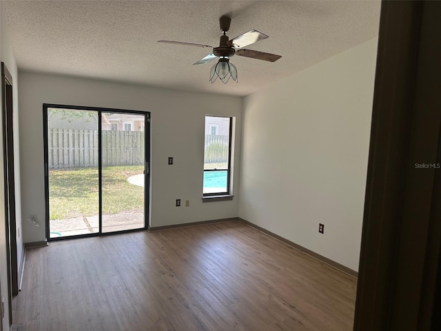 1412 Wexford Dr N, Palm Harbor, FL 34683 - spare room featuring a textured ceiling, wood finished floors, and a wealth of natural light