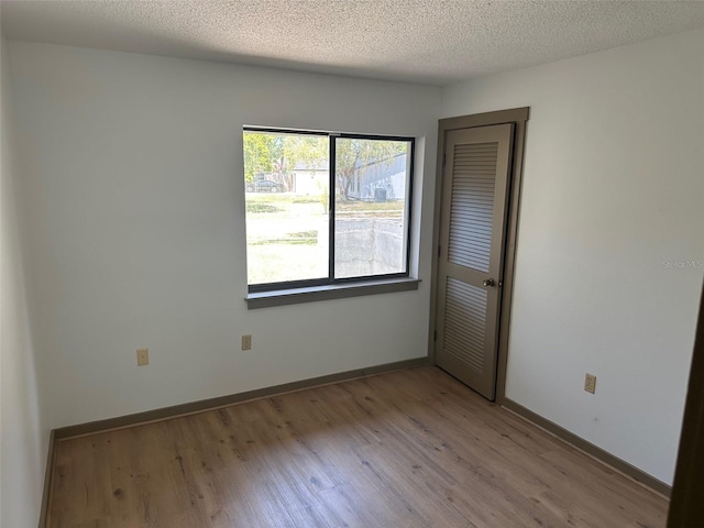 1412 Wexford Dr N, Palm Harbor, FL 34683 - unfurnished room with a textured ceiling, baseboards, and light wood finished floors