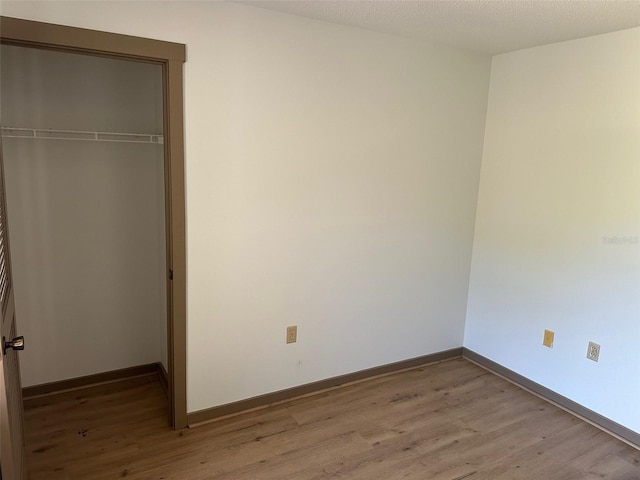 1412 Wexford Dr N, Palm Harbor, FL 34683 - unfurnished bedroom featuring light wood-style floors, baseboards, and a closet