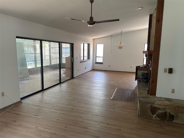 1412 Wexford Dr N, Palm Harbor, FL 34683 - unfurnished living room with a textured ceiling, baseboards, ceiling fan with notable chandelier, and wood finished floors