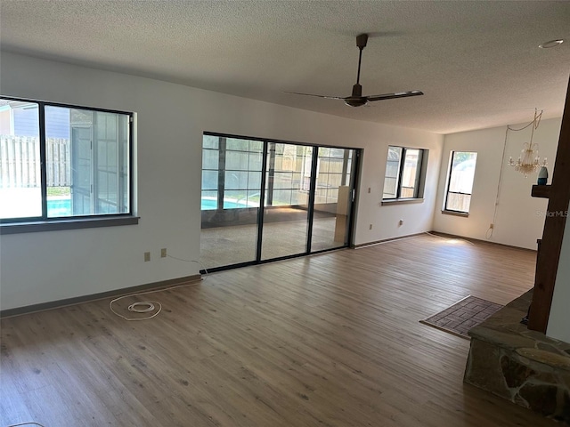 1412 Wexford Dr N, Palm Harbor, FL 34683 - unfurnished living room with baseboards, a textured ceiling, wood finished floors, and ceiling fan with notable chandelier