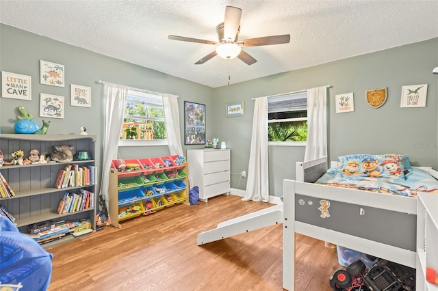 2400 Commack Ct, New Port Richey, FL 34655 - bedroom featuring wood finished floors, a textured ceiling, and a ceiling fan