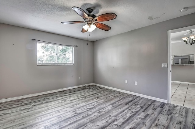4030 Casa Del Sol Way, New Port Richey, FL 34655 - empty room with a textured ceiling, wood finished floors, baseboards, and ceiling fan with notable chandelier