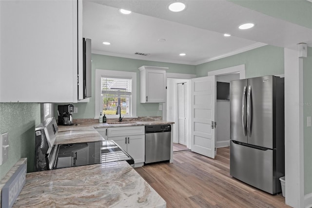 kitchen featuring stainless steel appliances, visible vents, ornamental molding, a sink, and white cabinetry
