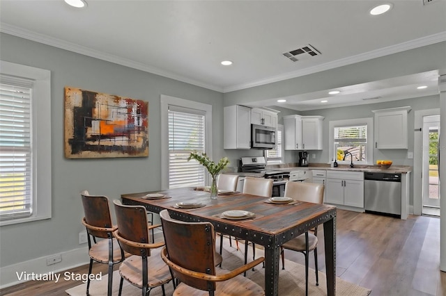 dining area featuring light wood finished floors, visible vents, and ornamental molding