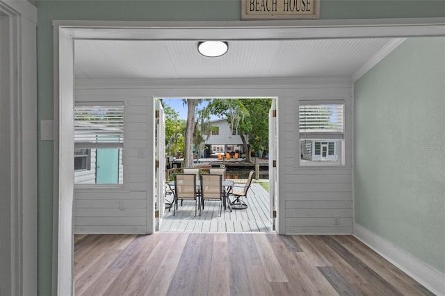 doorway to outside featuring baseboards, crown molding, and wood finished floors