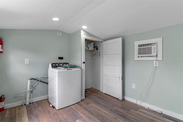 washroom featuring laundry area, wood finished floors, an AC wall unit, washer / dryer, and baseboards