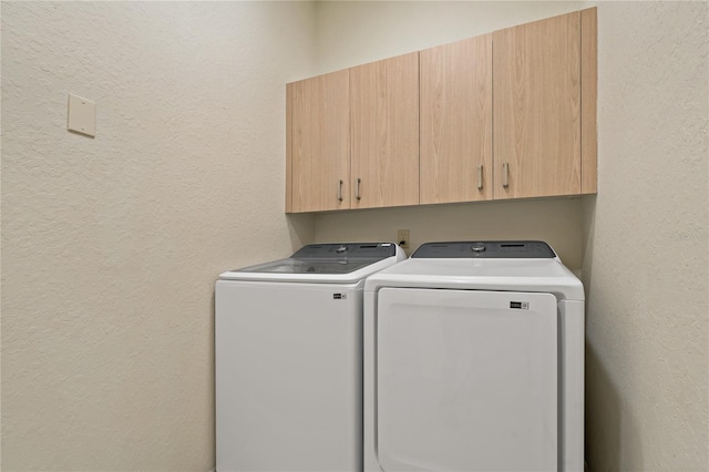 laundry room with cabinet space, washing machine and dryer, and a textured wall