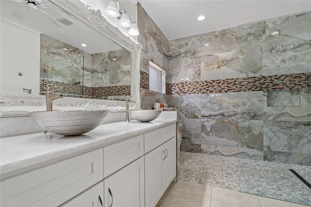 full bath featuring a marble finish shower, double vanity, tile walls, and tile patterned floors