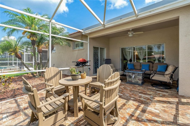 view of patio / terrace with a lanai, a ceiling fan, an outdoor living space with a fire pit, and outdoor dining space