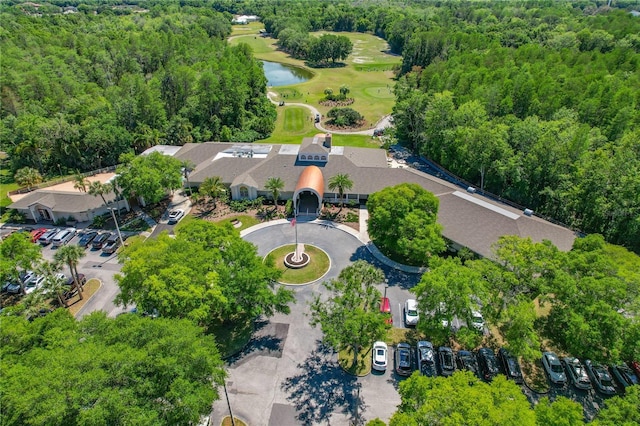 drone / aerial view of a nearby body of water, a golf club, and a forest