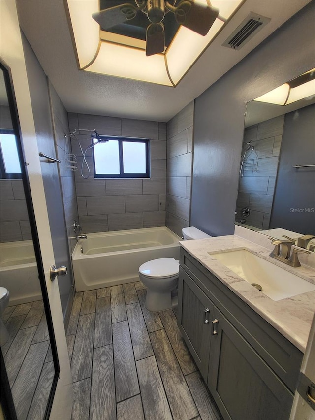 13111 Sheridan Dr, Hudson, FL 34667 - bathroom with toilet, wood tiled floors, vanity, washtub / shower combination, and ceiling fan