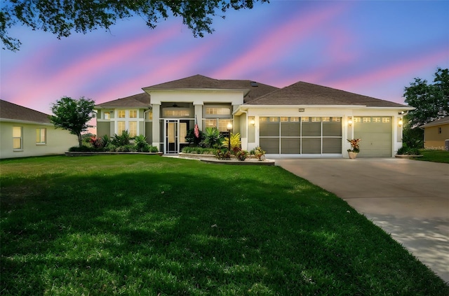 prairie-style house with a garage, stucco siding, a front yard, and concrete driveway