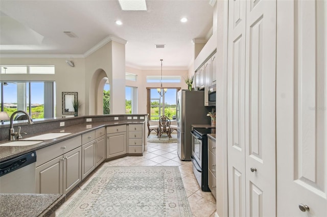 kitchen with ornamental molding, a sink, appliances with stainless steel finishes, light tile patterned floors, and a notable chandelier