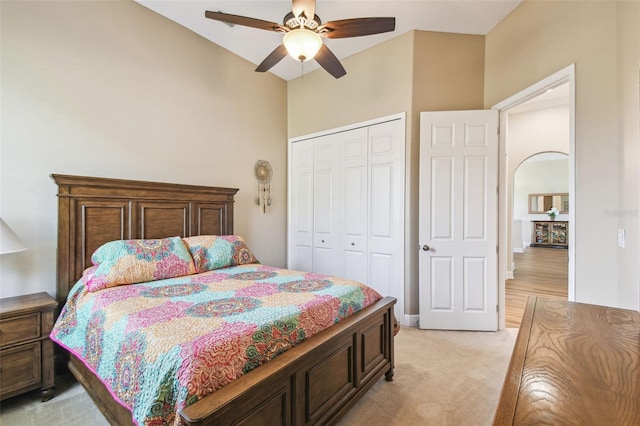 bedroom with arched walkways, a ceiling fan, a closet, and light colored carpet