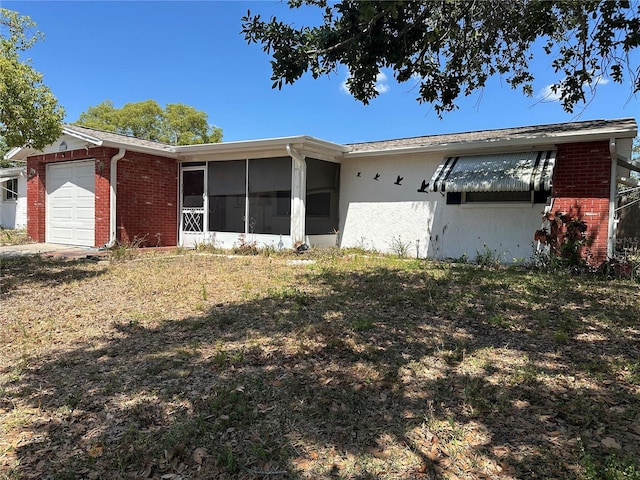 single story home with brick siding, an attached garage, and a sunroom