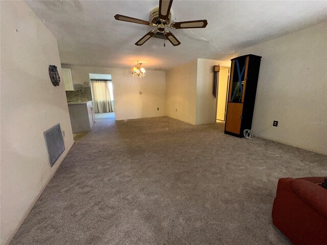 unfurnished living room with carpet floors, visible vents, ceiling fan with notable chandelier, and a fireplace