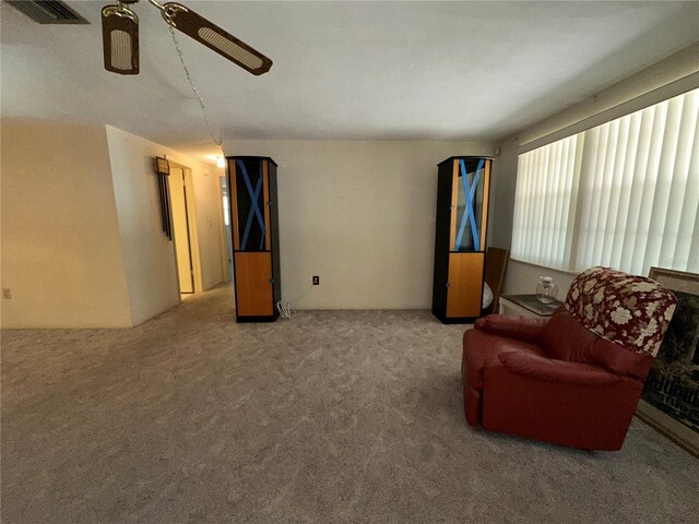 living room with ceiling fan, visible vents, and carpet