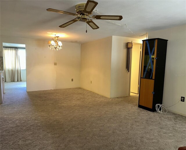 empty room with carpet floors and ceiling fan with notable chandelier