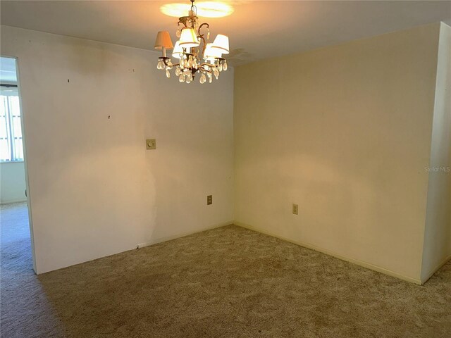 empty room with carpet and a notable chandelier