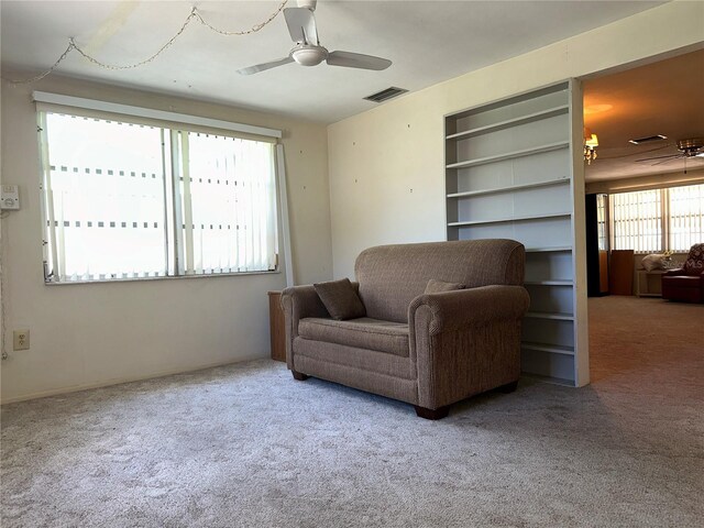 living area with visible vents, a ceiling fan, and carpet