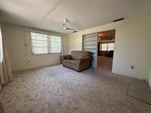living area featuring visible vents, carpet, ceiling fan, and built in features