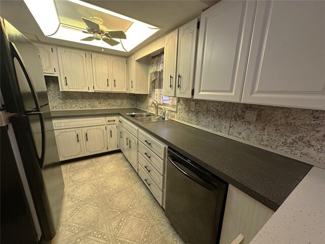 kitchen featuring dark countertops, a sink, dishwasher, freestanding refrigerator, and a ceiling fan
