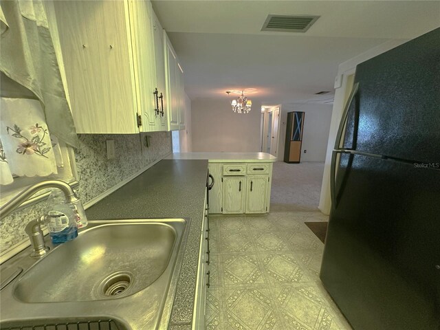 kitchen featuring a sink, a chandelier, freestanding refrigerator, a peninsula, and visible vents