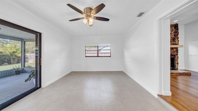 spare room featuring ceiling fan, visible vents, and a stone fireplace