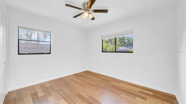 empty room featuring a ceiling fan, baseboards, and light wood-type flooring