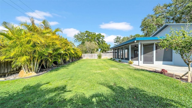 view of yard featuring a ceiling fan, a fenced backyard, and a sunroom