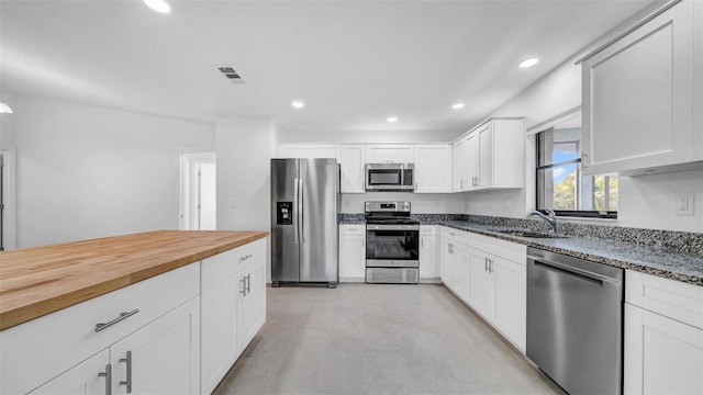 kitchen with appliances with stainless steel finishes, a sink, recessed lighting, white cabinetry, and visible vents