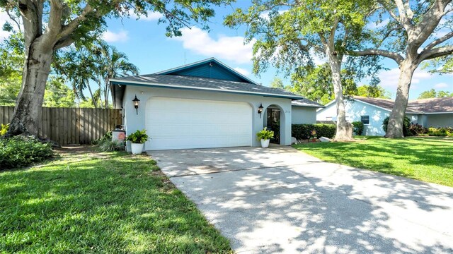 single story home featuring driveway, a garage, fence, a front lawn, and stucco siding