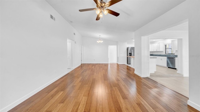 unfurnished living room featuring baseboards, visible vents, light wood finished floors, and ceiling fan with notable chandelier