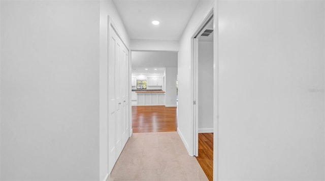 corridor with light wood-style floors, baseboards, and recessed lighting