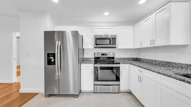 kitchen with white cabinets, recessed lighting, appliances with stainless steel finishes, and dark stone countertops