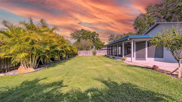 view of yard featuring a ceiling fan, a fenced backyard, and a sunroom