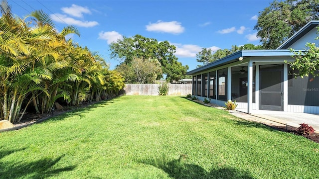 view of yard featuring a sunroom, a fenced backyard, and ceiling fan