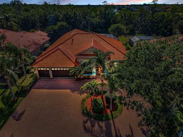 1033 Tuscany Dr, Trinity, FL 34655 - mediterranean / spanish home with a tiled roof, driveway, a wooded view, and a garage